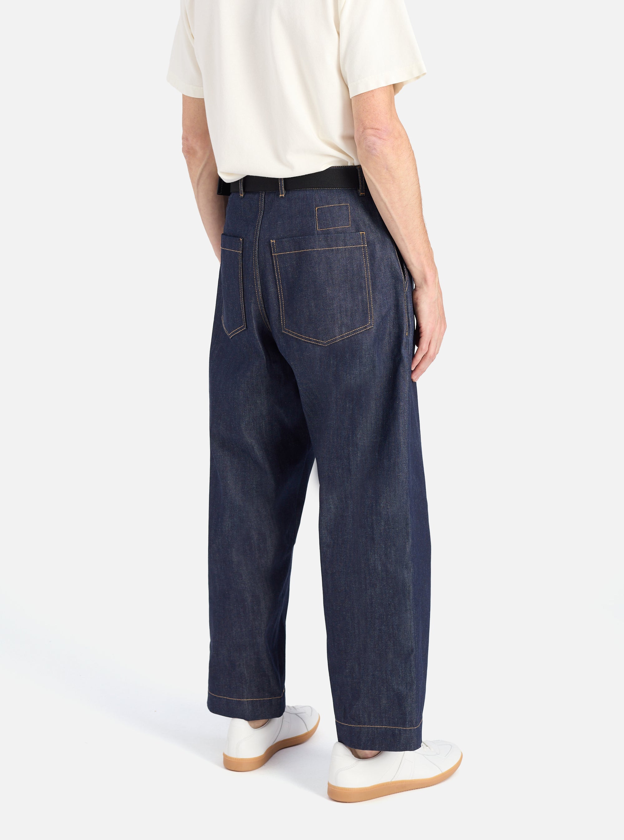 Back view of a model wearing Indigo 13oz Selvedge Denim Duke Pant, a dark wash, wide-leg jean.  Shot in a studio with a white background.