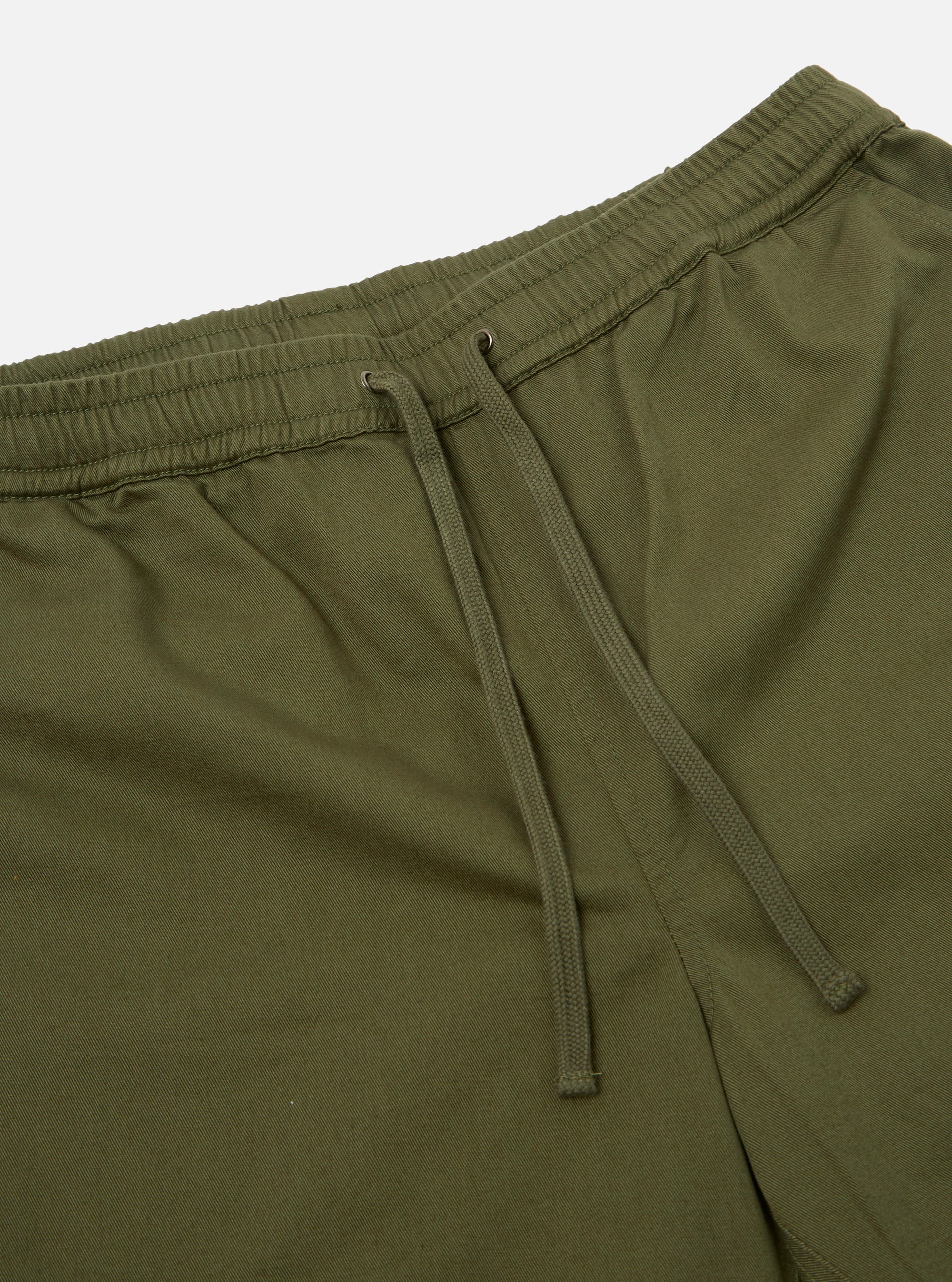 The Light Olive Twill Beach Short is shown from the back, highlighting the two rear patch pockets and the elasticated waistband. The shorts are displayed as a flat lay against a plain white background.