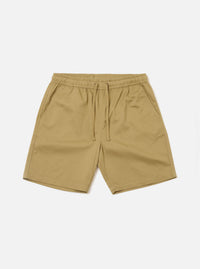 The Sand Twill Beach Short is presented as a flat lay against a solid white background. These light beige shorts feature an elasticated waistband with an internal drawstring and two large patch pockets on the front. The cotton twill fabric has a visible diagonal weave.