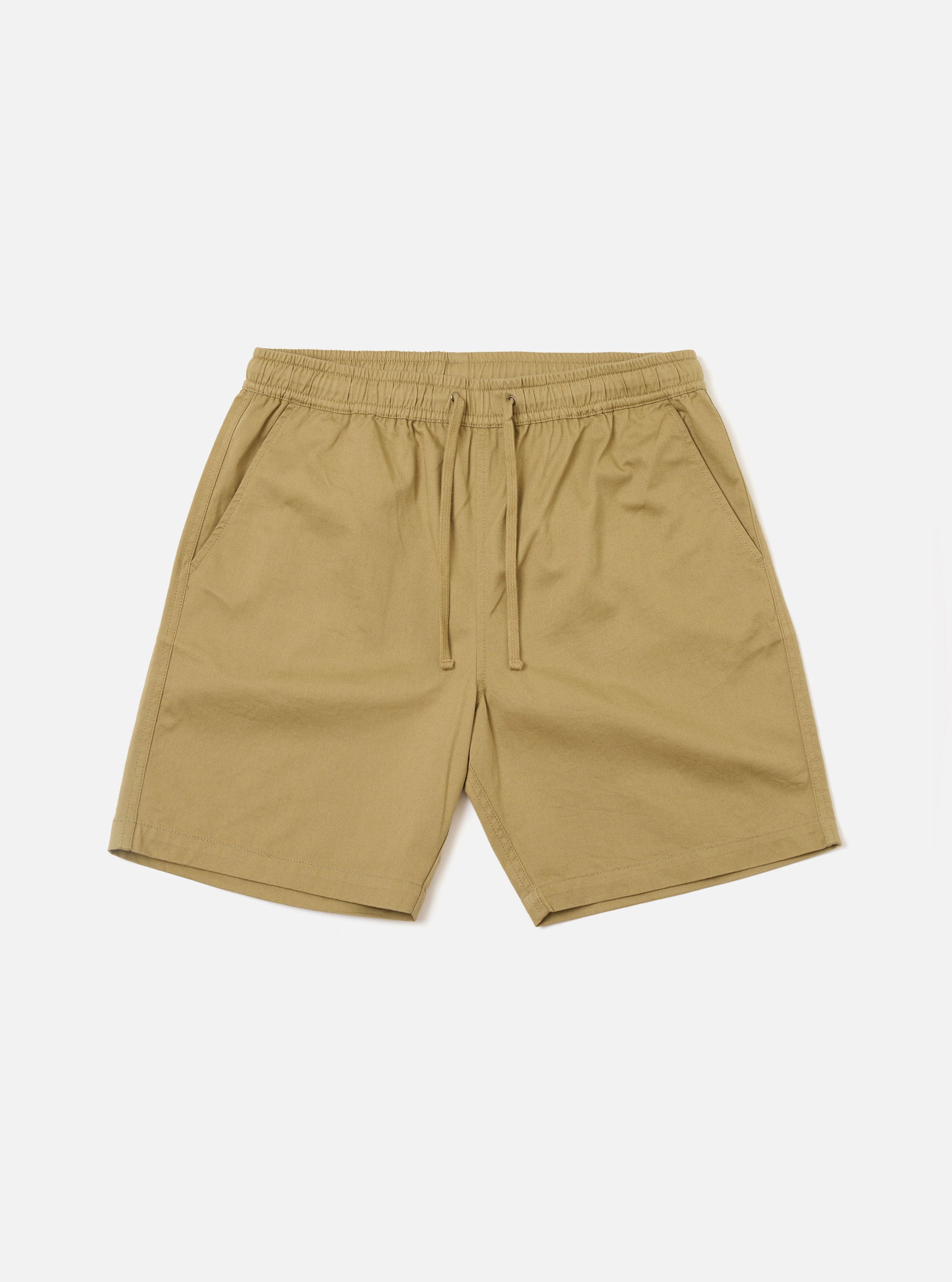 The Sand Twill Beach Short is presented as a flat lay against a solid white background. These light beige shorts feature an elasticated waistband with an internal drawstring and two large patch pockets on the front. The cotton twill fabric has a visible diagonal weave.