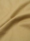 A close-up swatch of the Sand Twill Beach Short highlights the texture and diagonal weave of the sand-colored twill fabric. The material fills the frame, providing a detailed view of the garment's color and construction.