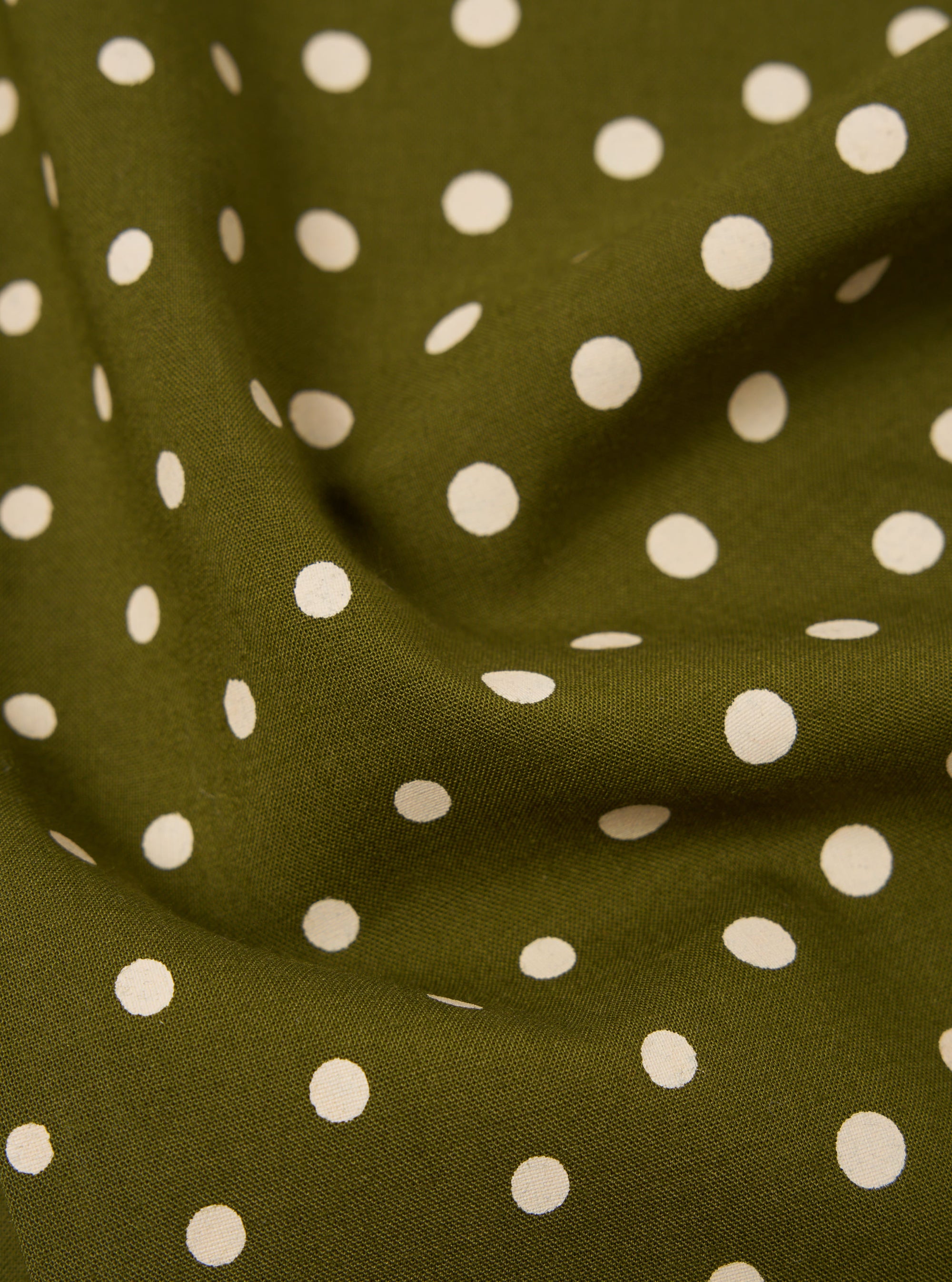 Close-up of a Green Dot Print Short Scarf. The scarf is olive green with white polka dots. The fabric is draped to show texture.