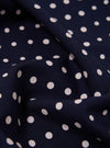 Close-up of a Navy Dot Print Short Scarf, showing the fabric's texture and pattern. The scarf is draped on a flat surface, highlighting the navy background and white polka dots.