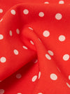 Close-up of an Orange Dot Print Short Scarf. The red fabric has white polka dots and is draped to show texture. 