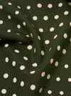 Close-up of an Olive Dot Print Short Scarf. The scarf is dark green with white polka dots. The fabric is draped to show texture.
