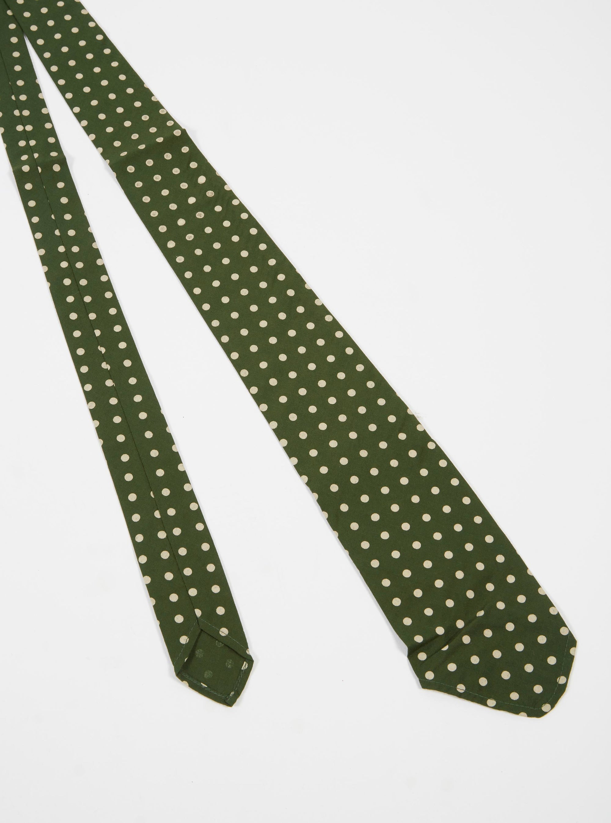 The Olive Dot Print Tie on a white background. The tie is olive green with small white dots. The tie is made of a soft, silky material.