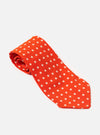 Close-up of an Orange Dot Print Tie on a white surface. The tie is orange with white polka dots. The background is plain white.