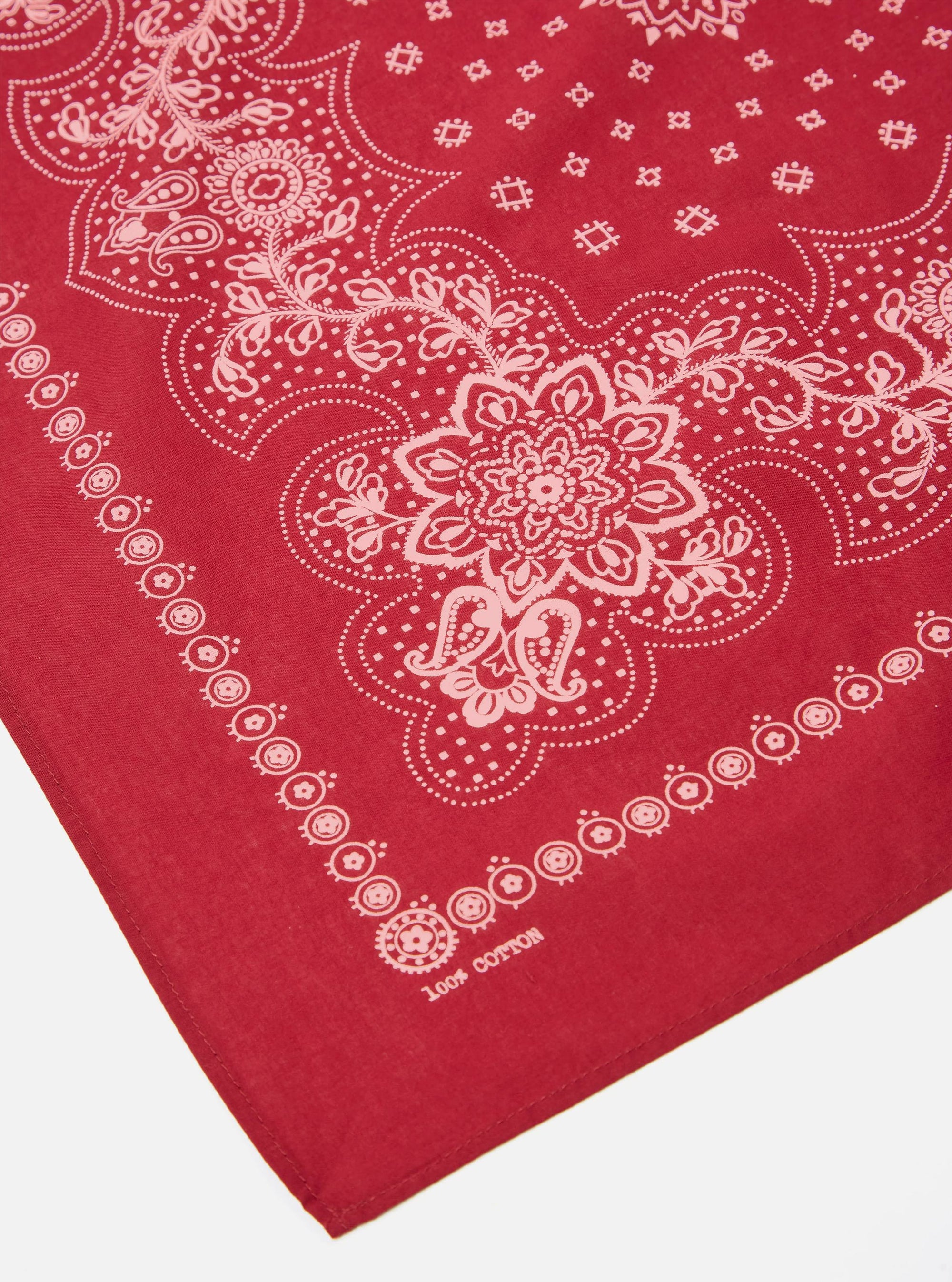 Close-up of a red 100% cotton Red Classic Bandana Neckerchief with a white paisley pattern on a white surface.