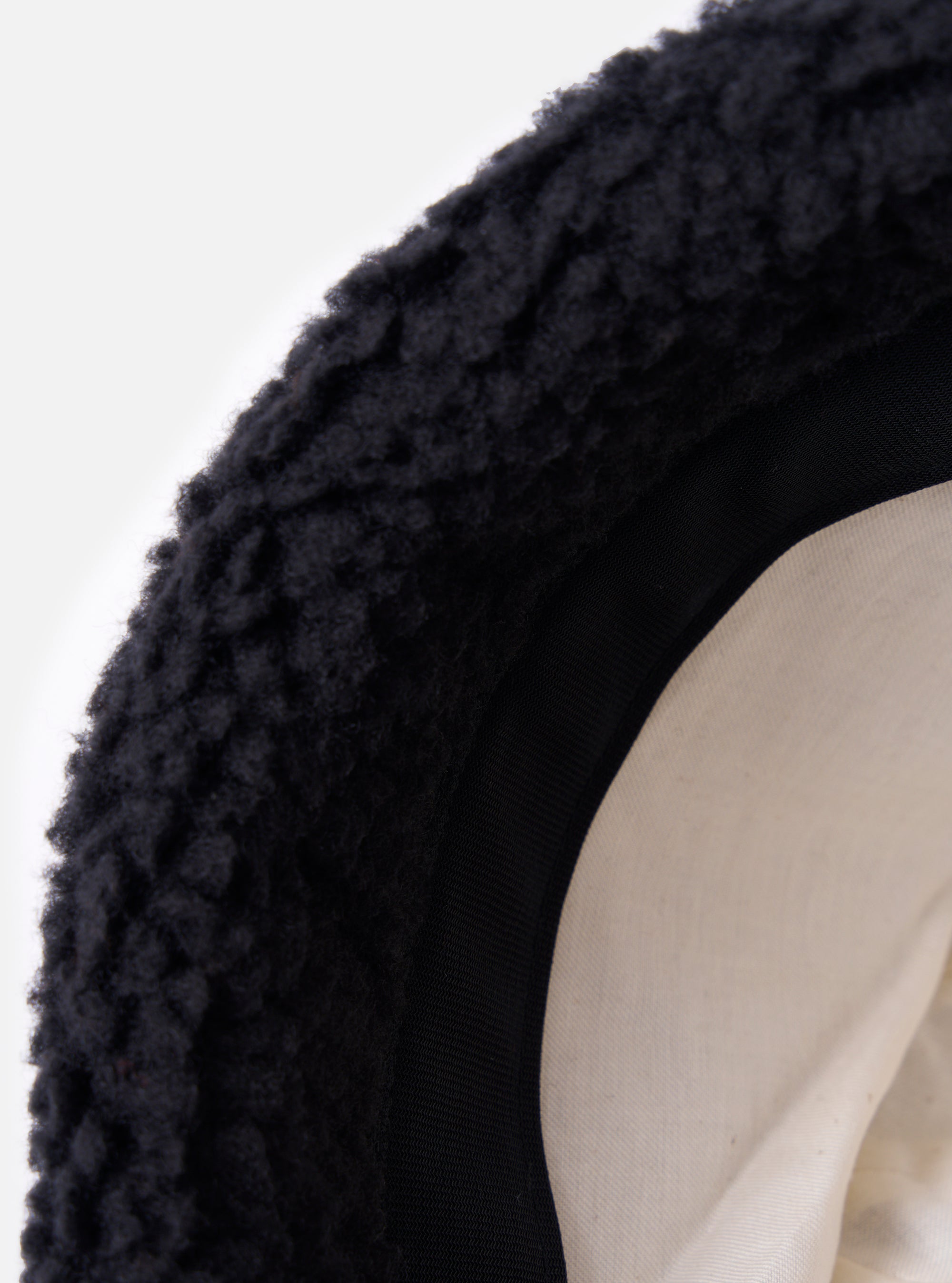 Close-up of the inside of a cableami® Black Toque Boa Cap. The hat has a black boa exterior, black trim, and a cream-colored lining. The background is a clean white.