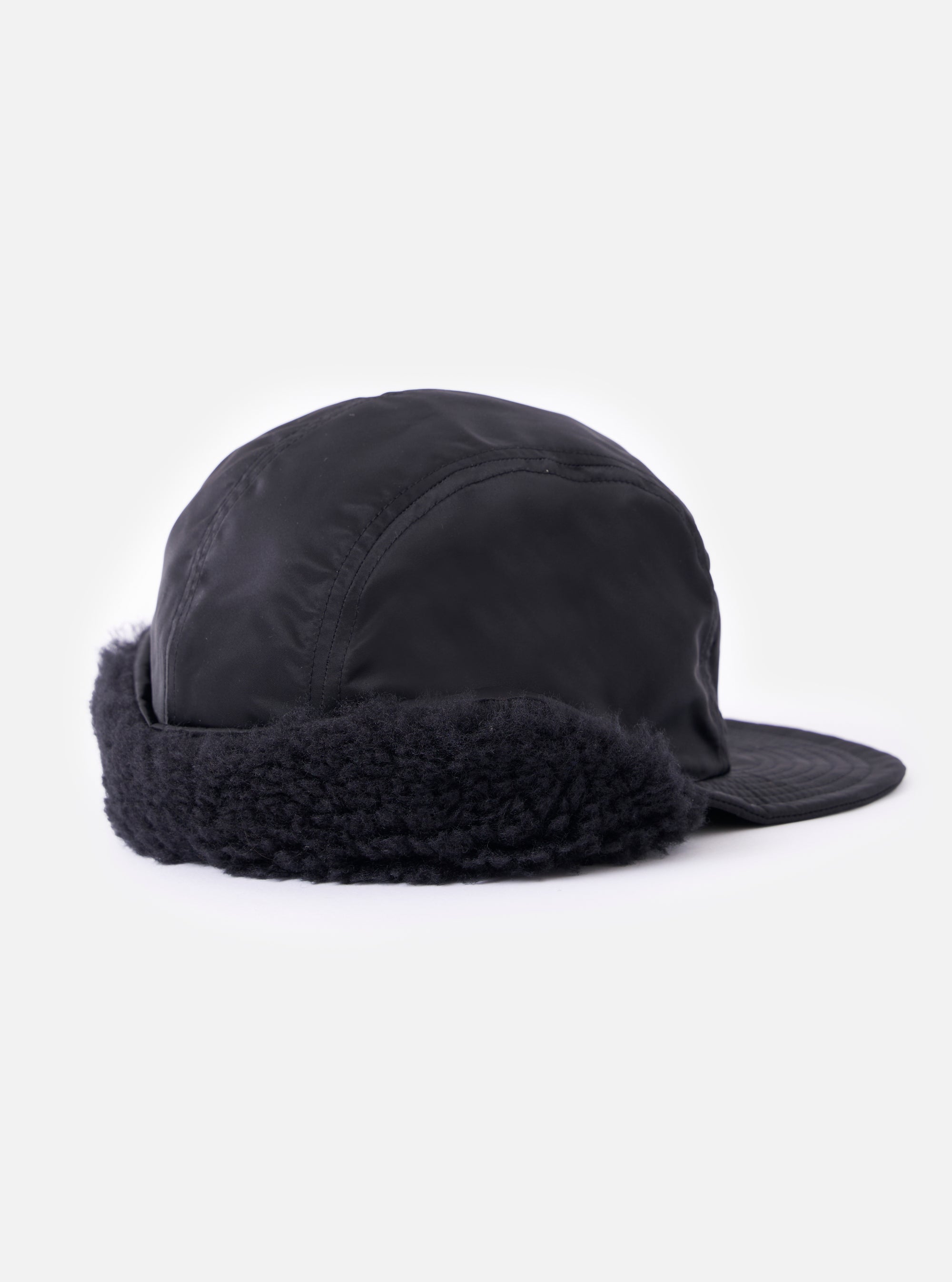 Side view of the cableami® Black Military Nylon Twill Cap on a white background. The cap features a black nylon twill construction and faux fur ear flaps.