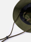 The cableami Dark Olive Baker Back Satin Cotton Metro Hat is shown as a flat lay against a plain white background. The image provides a detailed side-profile view of the hat, highlighting its six-panel construction, the slightly textured dark olive satin fabric, and the narrow, downward-sloping brim. A thin, dark adjustable chin strap with a plastic toggle is attached.