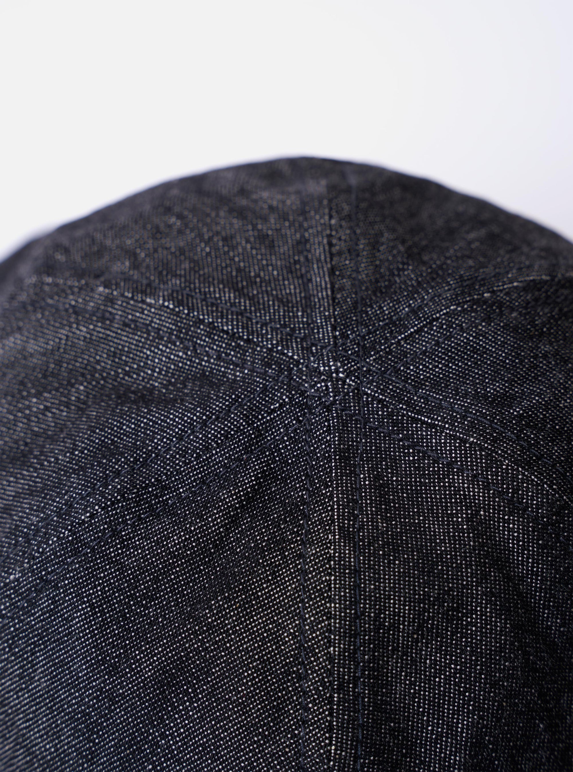 The cableami Black 10oz Denim Metro Hat is shown from a rear three-quarter angle as a flat lay against a plain white background. The image highlights the hat's rounded crown construction and the downward-sloping brim. The black denim fabric features visible tonal stitching throughout.