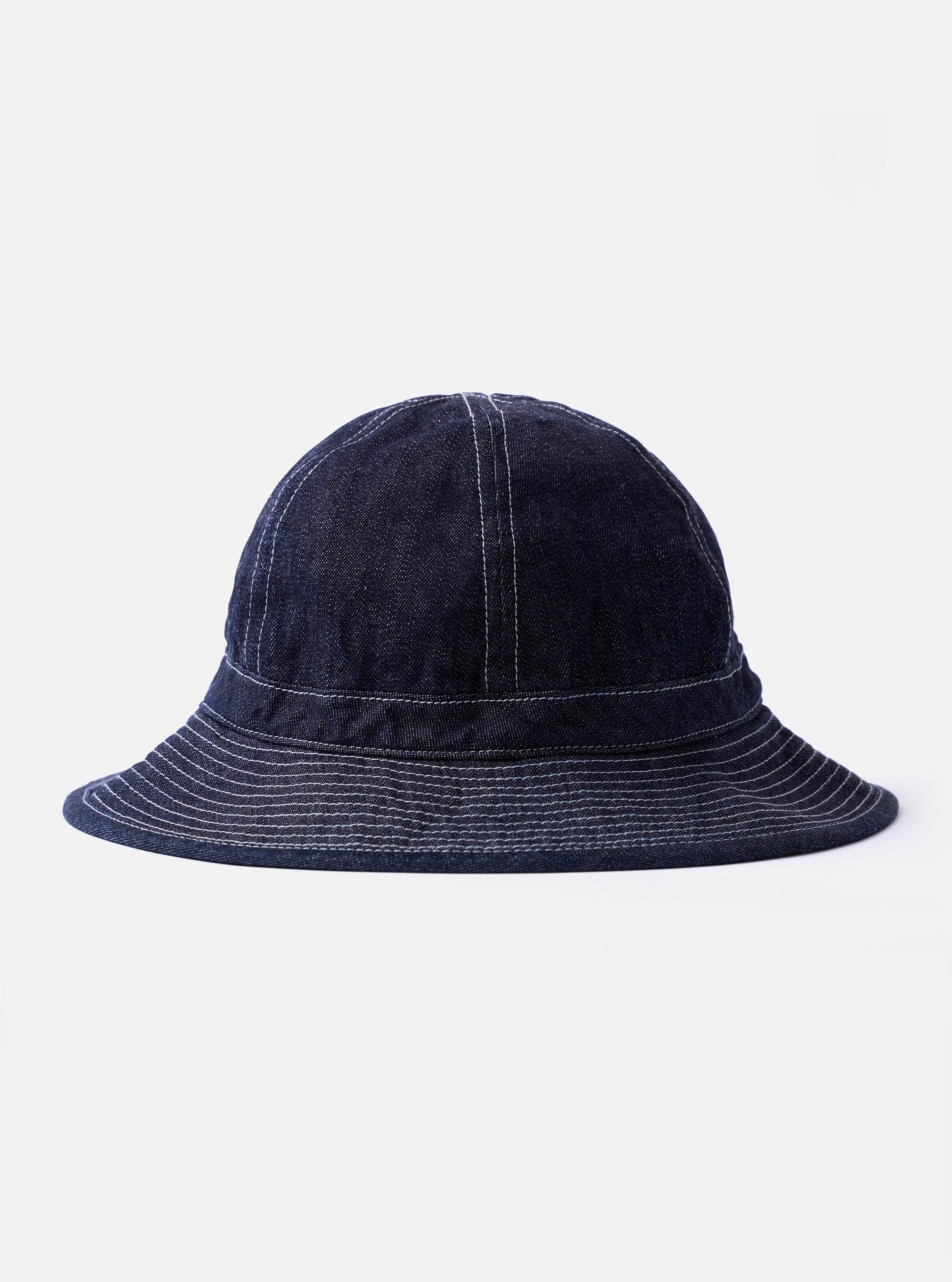 The cableami Indigo 10oz Denim Metro Hat is shown as a flat lay against a white background. The hat is made from a deep indigo blue denim and features a rounded crown, a downward-sloping brim with tonal topstitching, and an adjustable strap with a toggle.