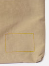 The master-piece x Universal Works Beige Canvas Sacoche is shown from a rear angle as a flat lay against a plain white background. The image highlights the adjustable olive green webbing shoulder strap and the back of the bag, which features a clean, rectangular silhouette in beige canvas.