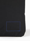The master-piece x Universal Works Black Canvas Sacoche is shown in a detail view as a flat lay against a plain white background. The image focuses on the adjustable black shoulder strap and the metal hardware, including a swivel lobster clasp and a slider buckle. The durable black canvas fabric and clean stitching of the bag's attachment point are clearly visible.