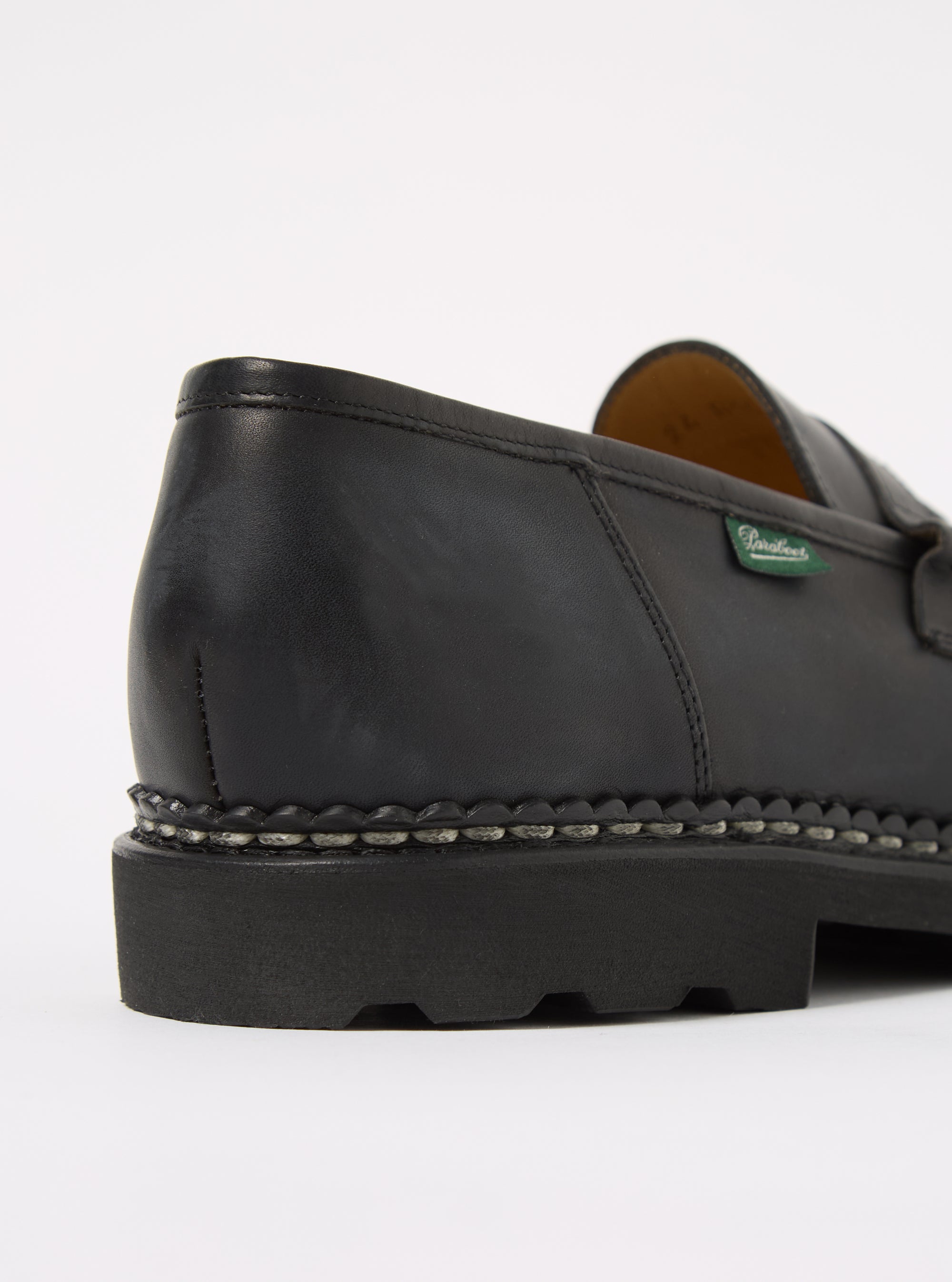 Close-up of a Paraboot Black Leather Reims Marche shoe on a white background. The black leather upper sits atop a thick black sole with a decorative welt.