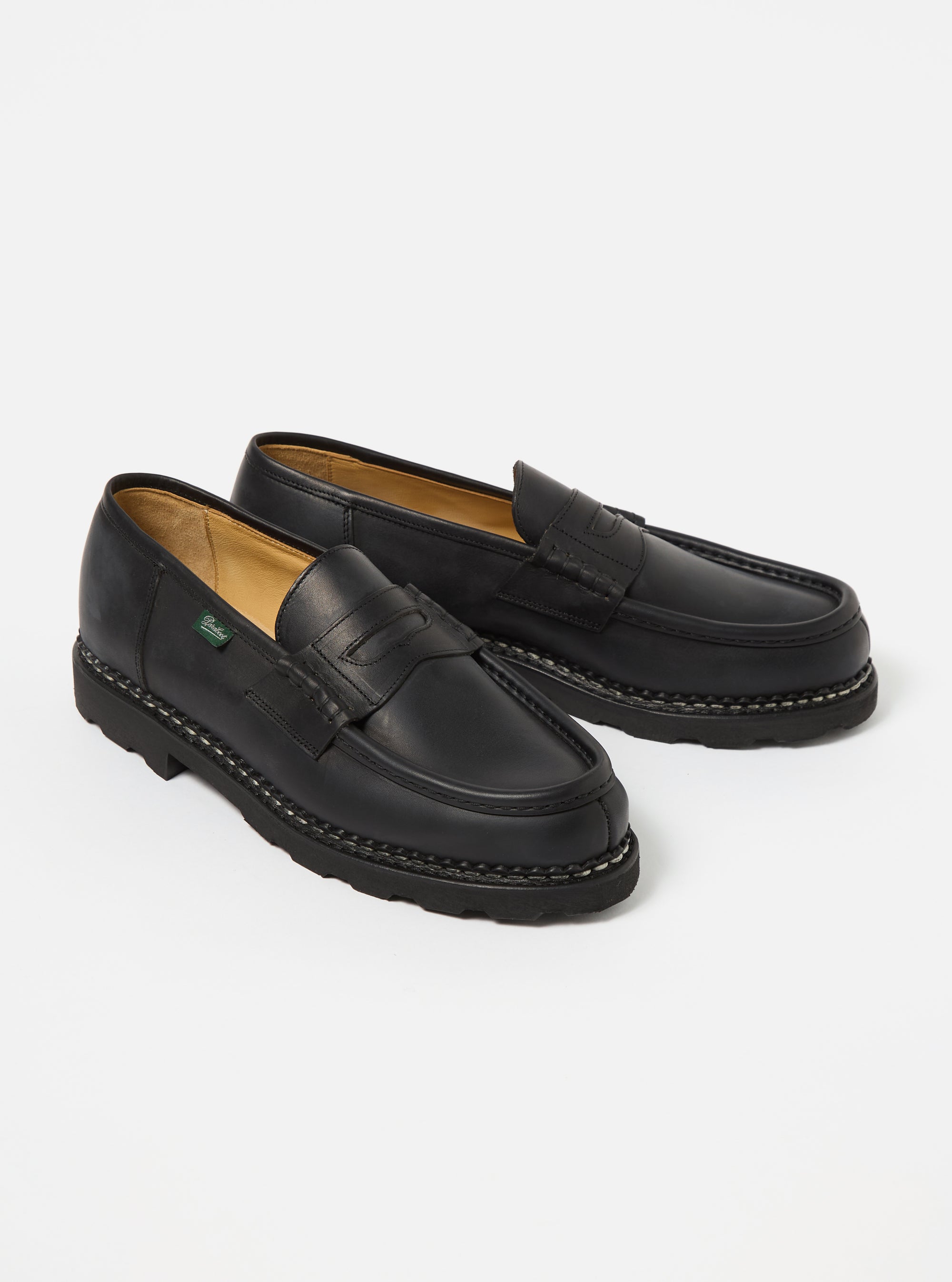 Paraboot Black Leather Reims Marche shoes on a white background. These classic black leather loafers feature a penny loafer strap and a durable rubber sole.