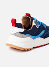 The Flower Mountain Navy/Azure Suede/Nylon Wave Man is shown from a rear angle as a flat lay against a plain white background. The image highlights the technical fabric upper in navy and azure blue, the webbing back pull tab, and the signature notched edge rubber gum sole in a tan color.