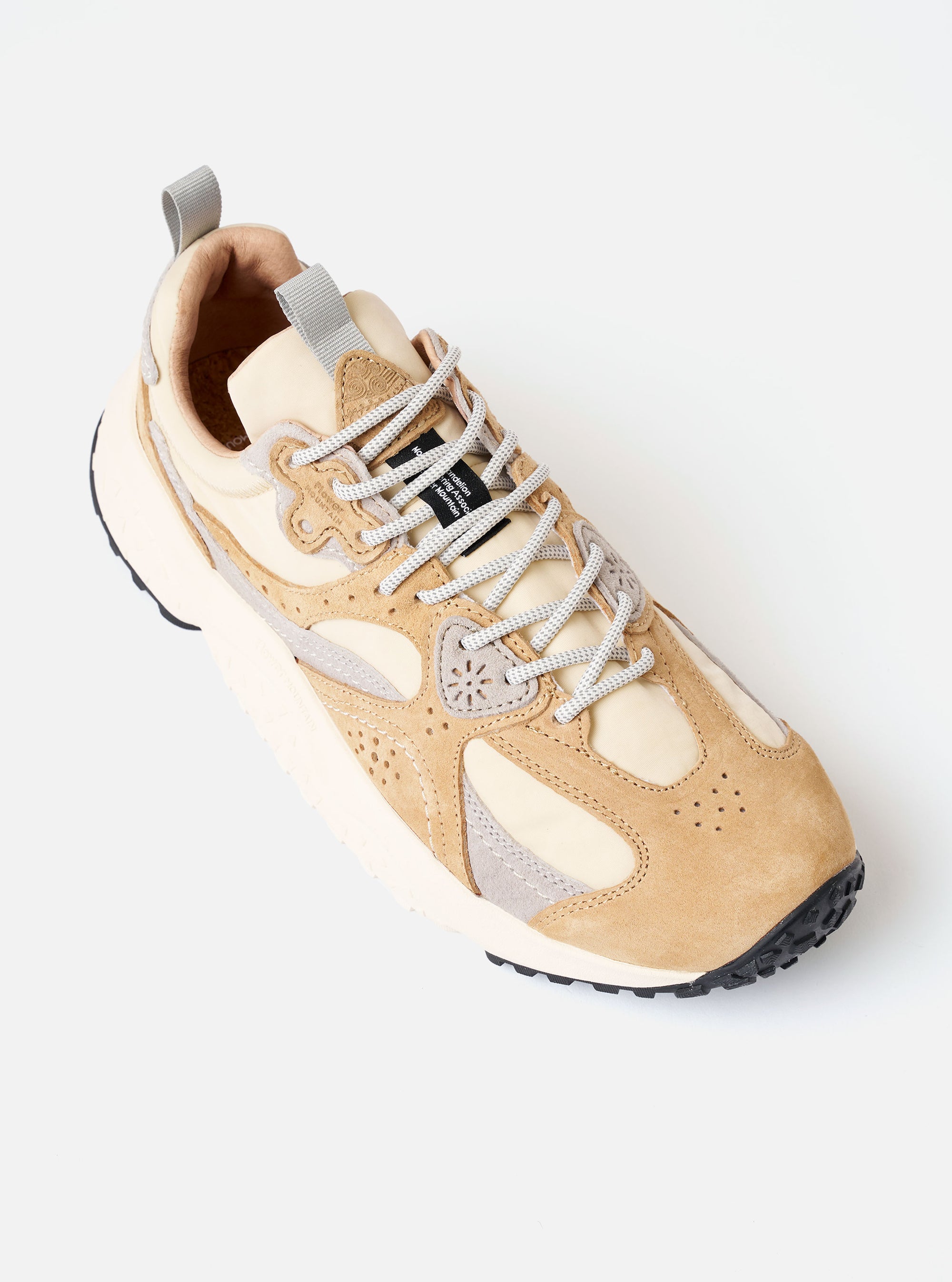 The Flower Mountain Beige/Cream/Light Grey Suede/Nylon Wave Uni is shown from a side profile against a plain white background. The sneaker features a multi-paneled upper with overlapping layers of beige and light grey suede over a cream nylon base. Notable details include trekking-style laces with flower-shaped eyelets, a webbing back pull tab, and a chunky, ultra-lightweight rubber sole with a signature notched edge.