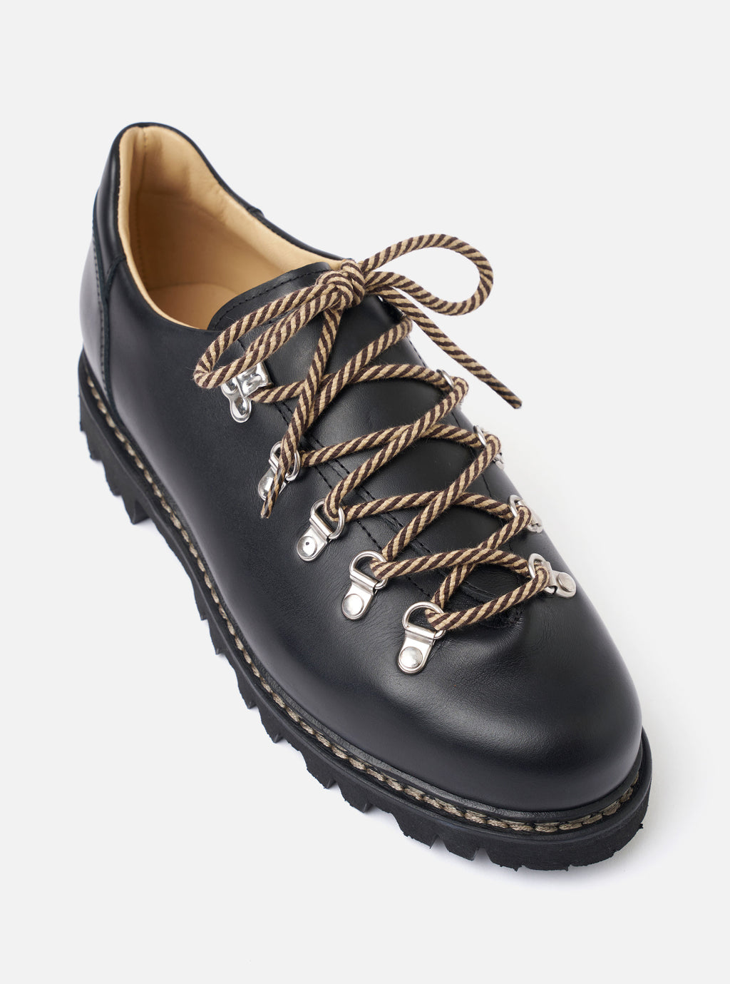 The Paraboot Black Leather Clusaz Jannu is shown from a side profile against a plain white background. The low-top shoe features a smooth black leather upper with silver-tone D-ring eyelets and black rope laces. The design includes a sturdy black rubber lug sole with visible Norwegian welt stitching and a rounded toe.