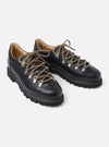 The Paraboot Black Leather Clusaz Jannu is shown from a side-profile angle as a flat lay against a plain white background. The image highlights the shoe's low-cut mountaineering silhouette, featuring a smooth black leather upper, silver D-ring metal eyelets with black rope laces, and a chunky black rubber lug sole with visible Norwegian welt stitching.