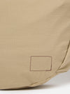 The master-piece x Universal Works Beige Large Canvas Shoulder Bag is shown from the back as a flat lay against a plain white background. The image highlights the adjustable webbed shoulder strap and the clean, rectangular construction of the bag's rear panel in a sand-colored beige fabric.