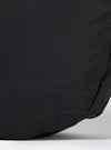 The master-piece x Universal Works Black Large Canvas Shoulder Bag is shown from the back as a flat lay against a plain white background. The image highlights the bag's large, rectangular shape and the textured black canvas material. A horizontal strap is attached across the middle of the back panel.