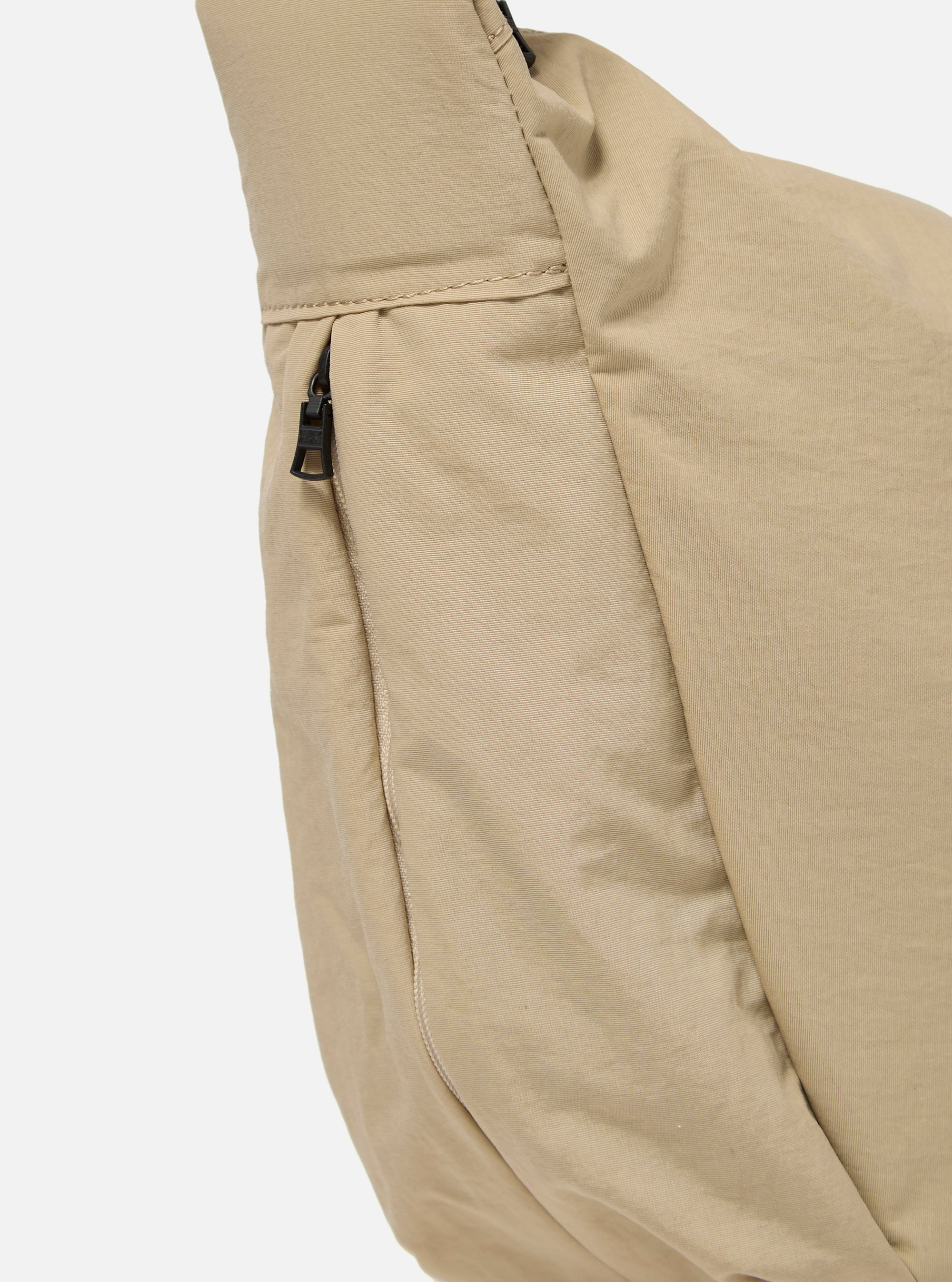 The master-piece x Universal Works Beige Medium Canvas Shoulder Bag is shown from the back as a flat lay against a plain white background. The image highlights the adjustable shoulder strap, a large rear compartment with a snap-button closure, and the durable beige canvas construction.