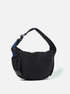 The master-piece x Universal Works Black Medium Canvas Shoulder Bag is shown from the back as a flat lay against a plain white background. The image highlights the adjustable black shoulder strap and the clean, rectangular construction of the bag's rear.