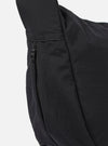 The master-piece x Universal Works Black Medium Canvas Shoulder Bag is shown from the back as a flat lay against a plain white background. The image highlights the adjustable black webbing shoulder strap attached with metal hardware and the clean, rectangular construction of the bag's rear. The canvas fabric has a smooth, matte black finish.