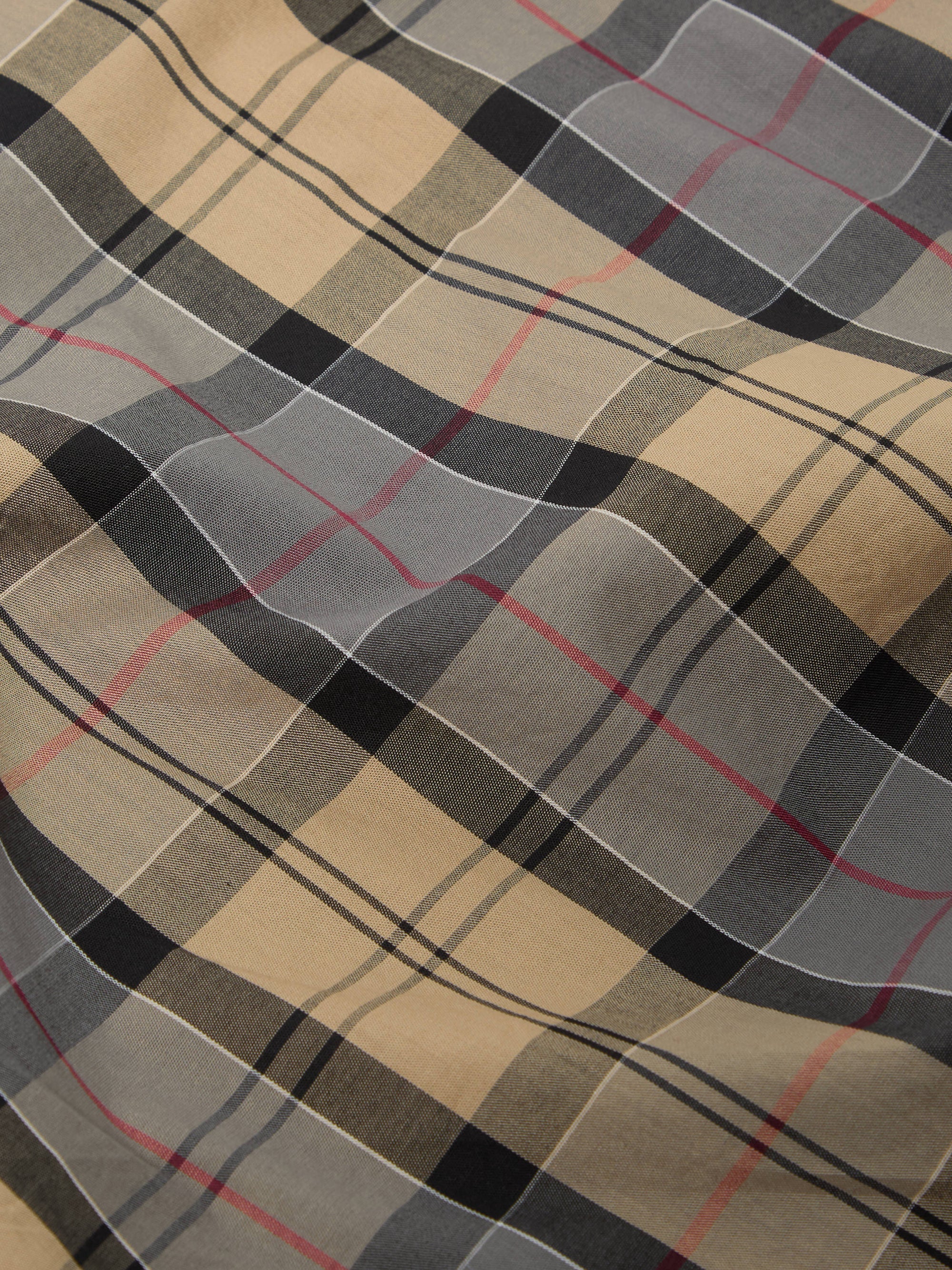Close-up of the Sand Tartan Check Pyjama Pant fabric. Features a beige, gray, and black plaid pattern with thin red stripes. The material is softly draped.