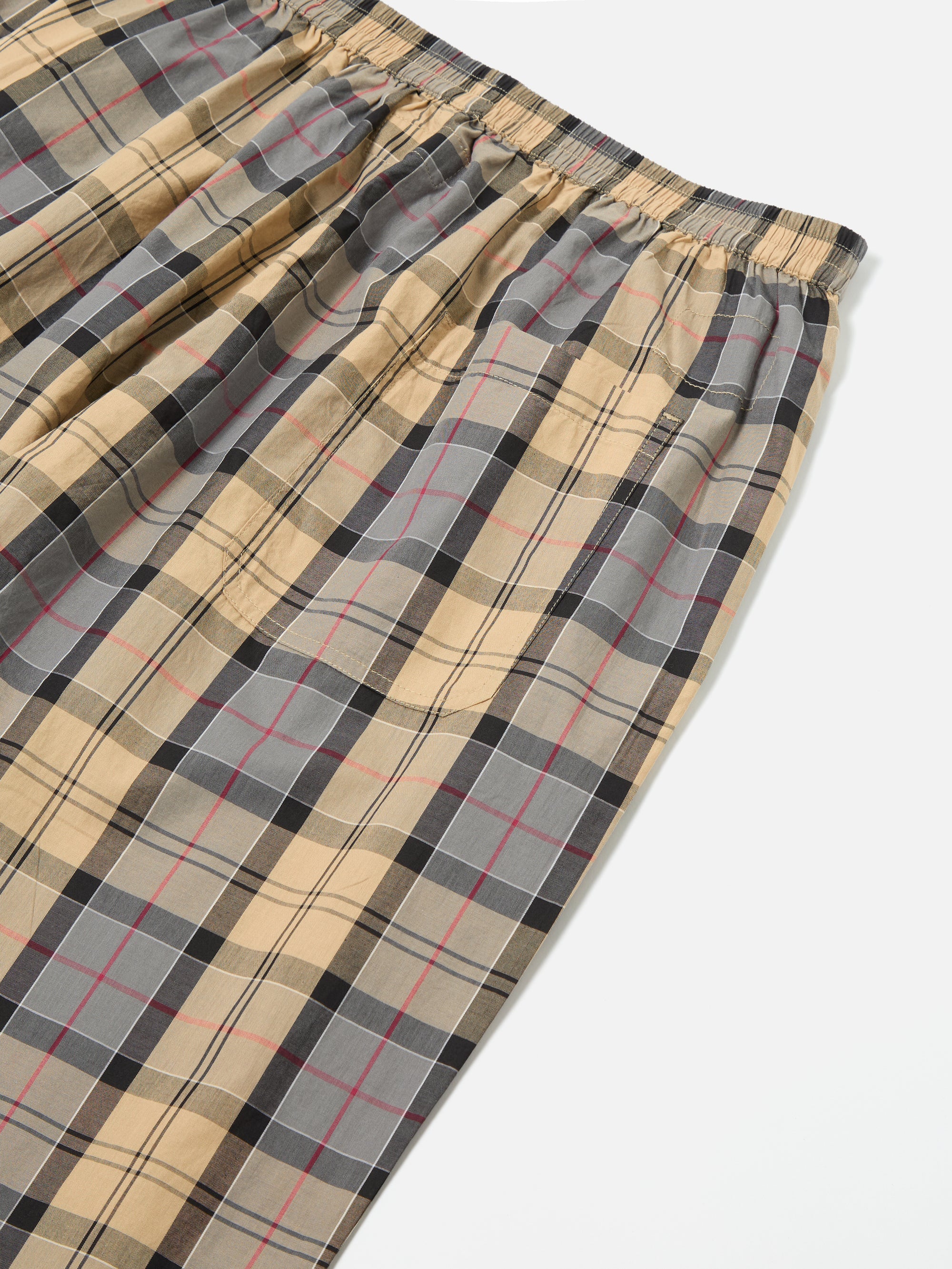 Close-up of the Sand Tartan Check Pyjama Pant on a white surface. The pattern features sand, gray, black, and red lines. Elastic waistband detail visible.