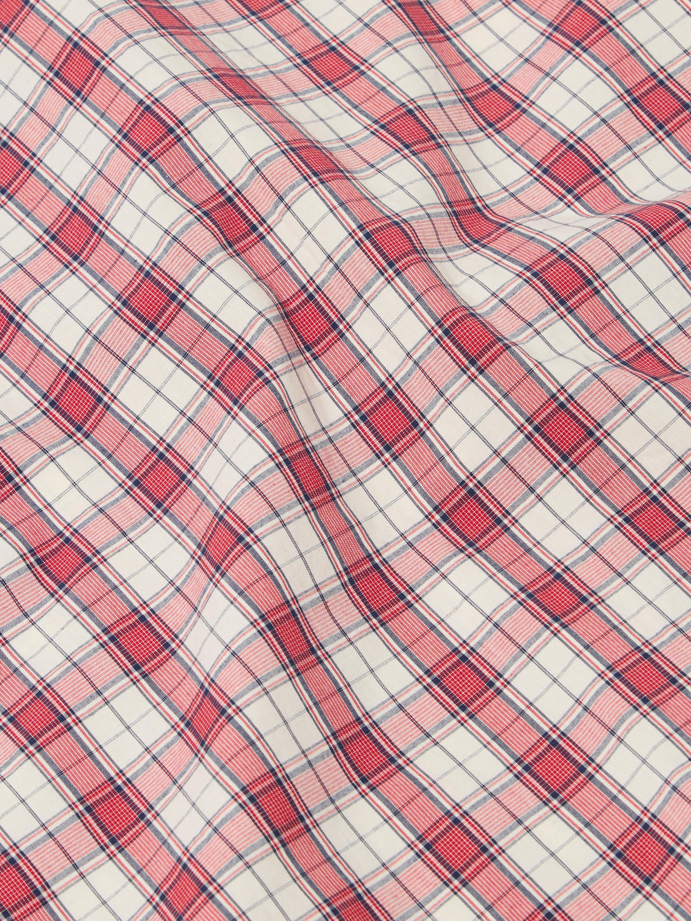 Close-up of the Red Cotton Check Pyjama Pant fabric. The red and blue plaid cotton is softly draped on a flat surface.