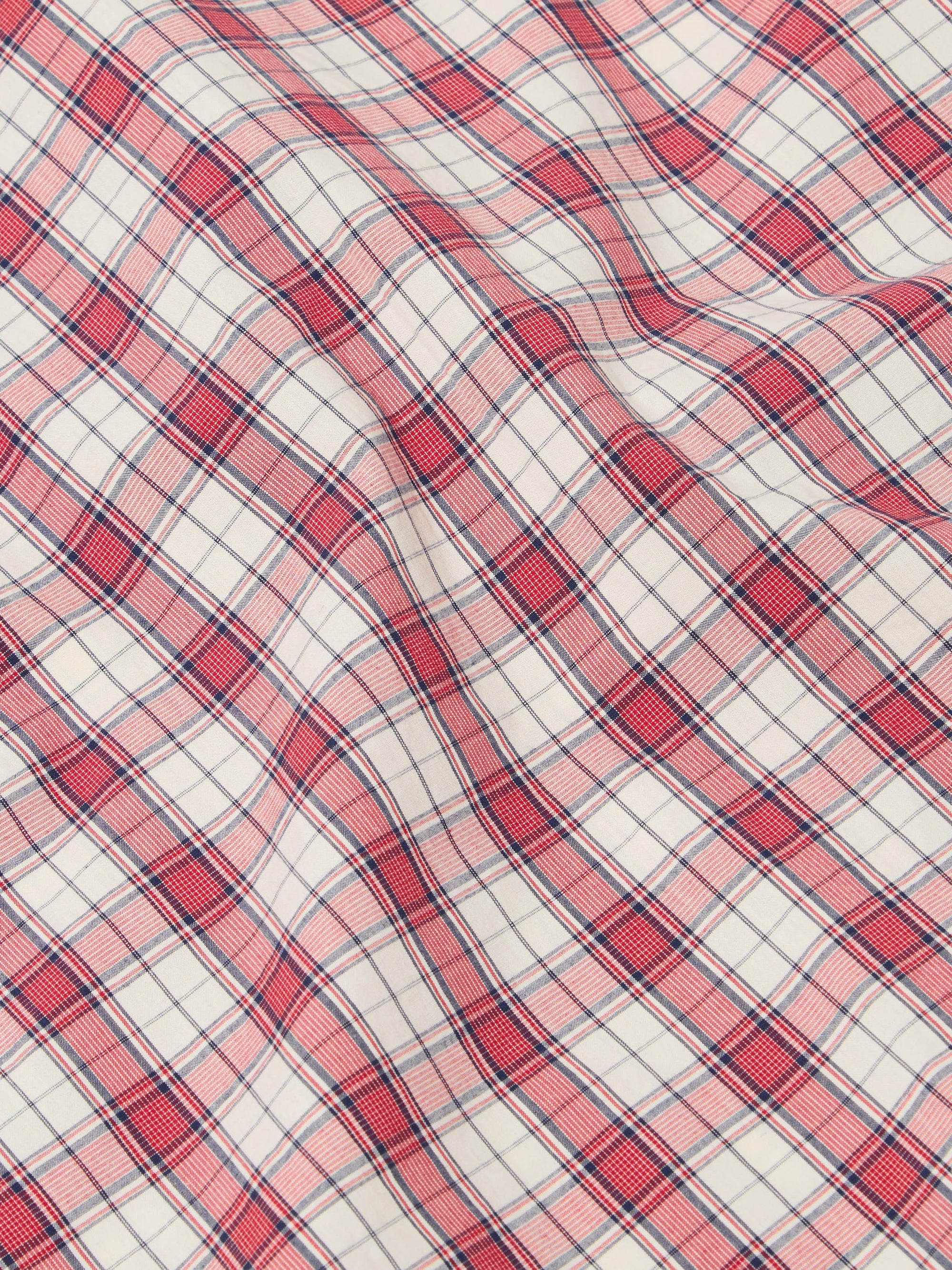 Close-up of the Red Cotton Check Pyjama Short fabric. The red and blue plaid cotton is softly draped on a flat surface.