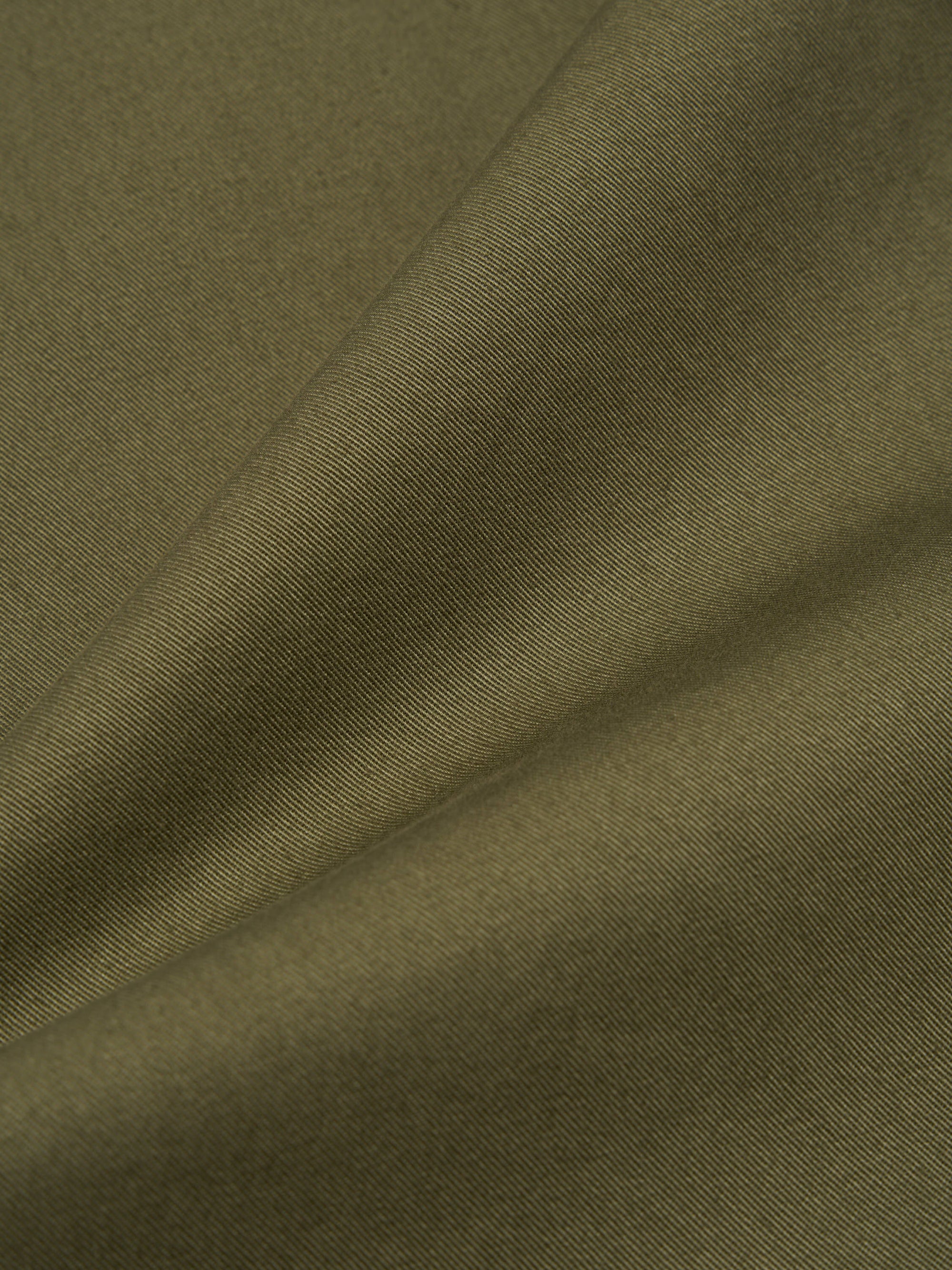 Close-up of the light olive twill fabric used for the Field Waistcoat. The material is draped to show texture and color. 