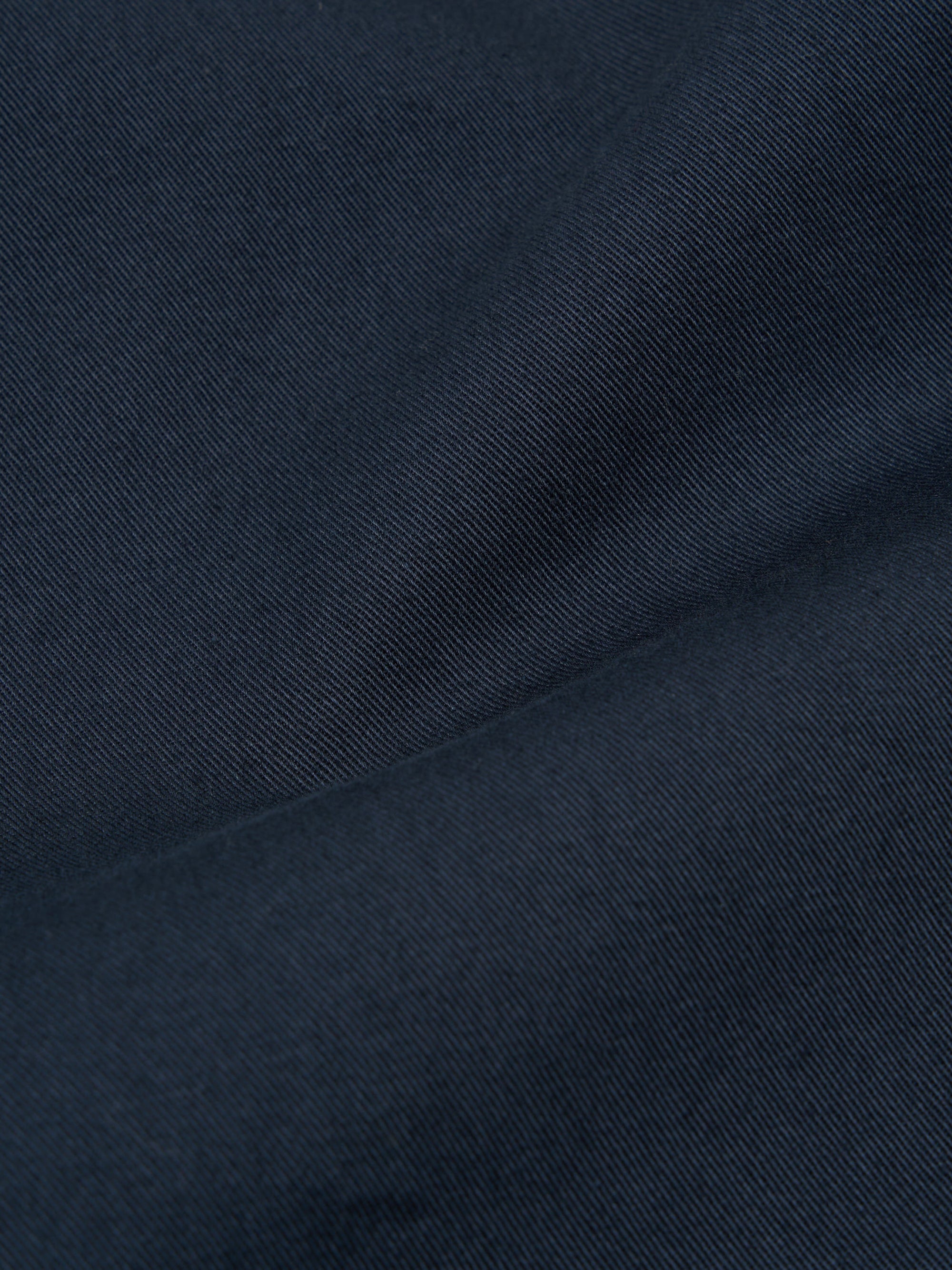 Close-up of the Navy Twill Fatigue Pant fabric. The twill weave is visible, showing the texture and color of the material. The pants are folded on a plain surface.
