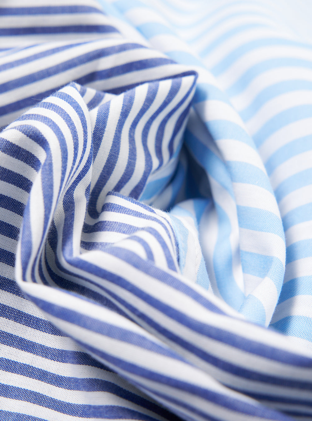 Close-up of the Blue Classic Mix Boxer Short fabric. Features blue and white stripes in a soft cotton blend. The material is artfully draped to showcase its texture.