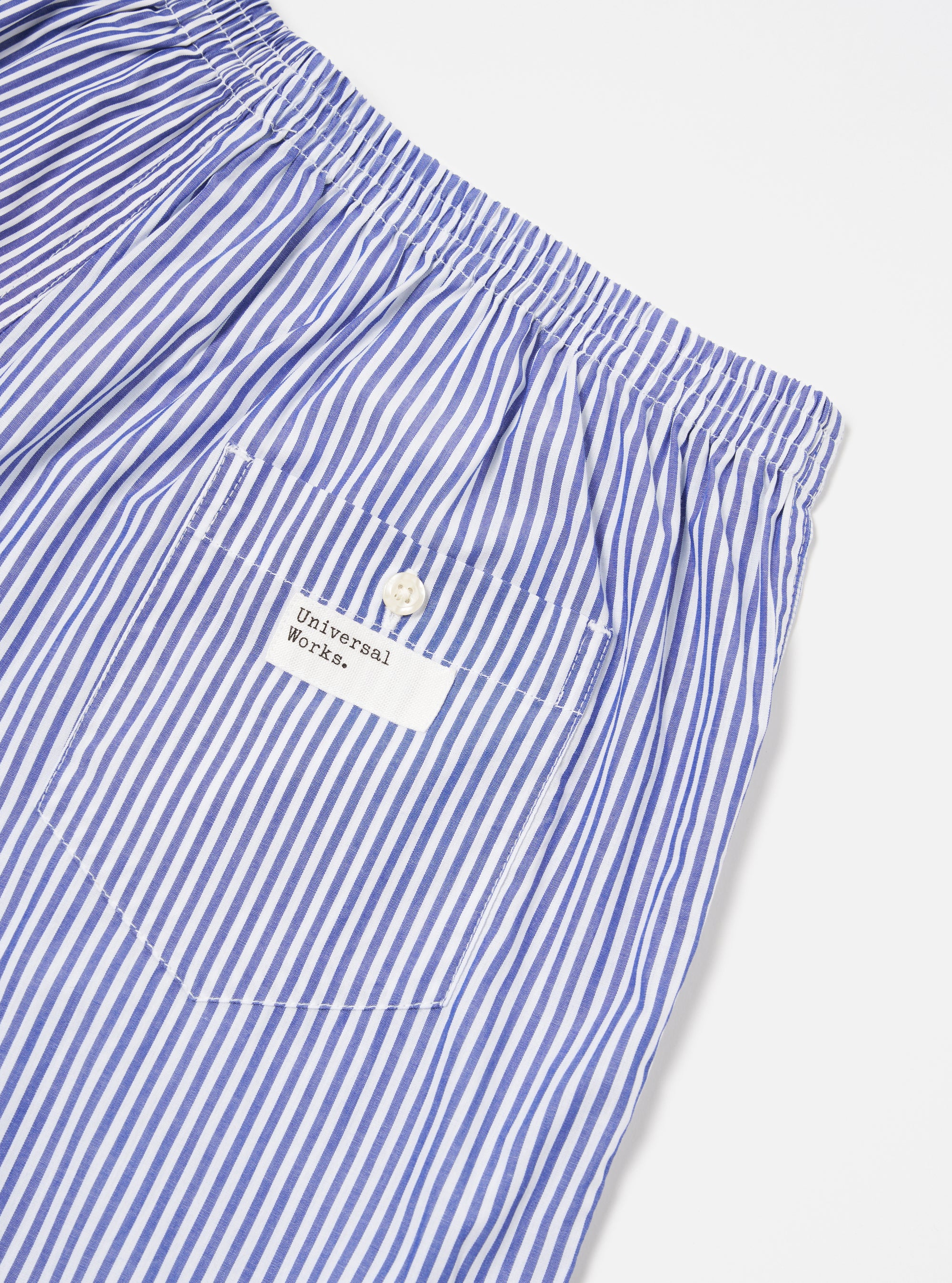 Close-up of the Blue Classic Mix Boxer Short on a white surface. The blue and white striped cotton boxer shorts feature an elastic waistband and a small pocket with a button.