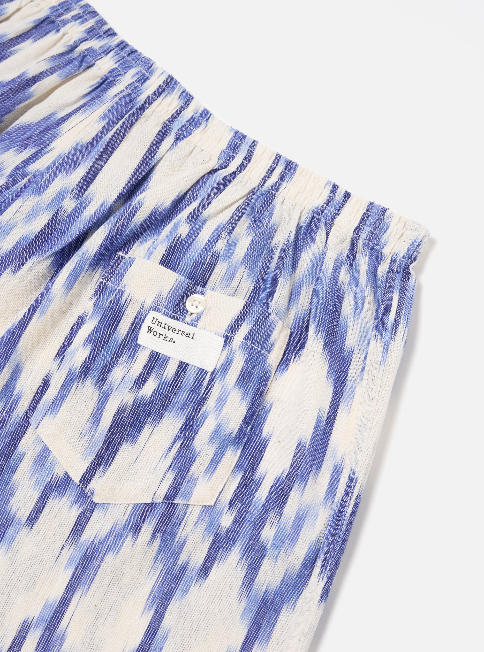Close-up of Ecru Ikat I Cotton Boxer Short on a white surface. Features blue ikat pattern, elastic waist, and pocket with button. Casual and comfortable.