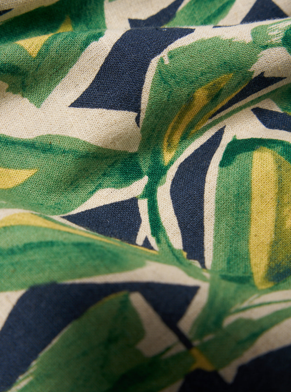 Close-up of the Navy Artist Flower Lincot Boxer Short fabric. Features a green, yellow, and navy floral pattern on a light beige woven material.