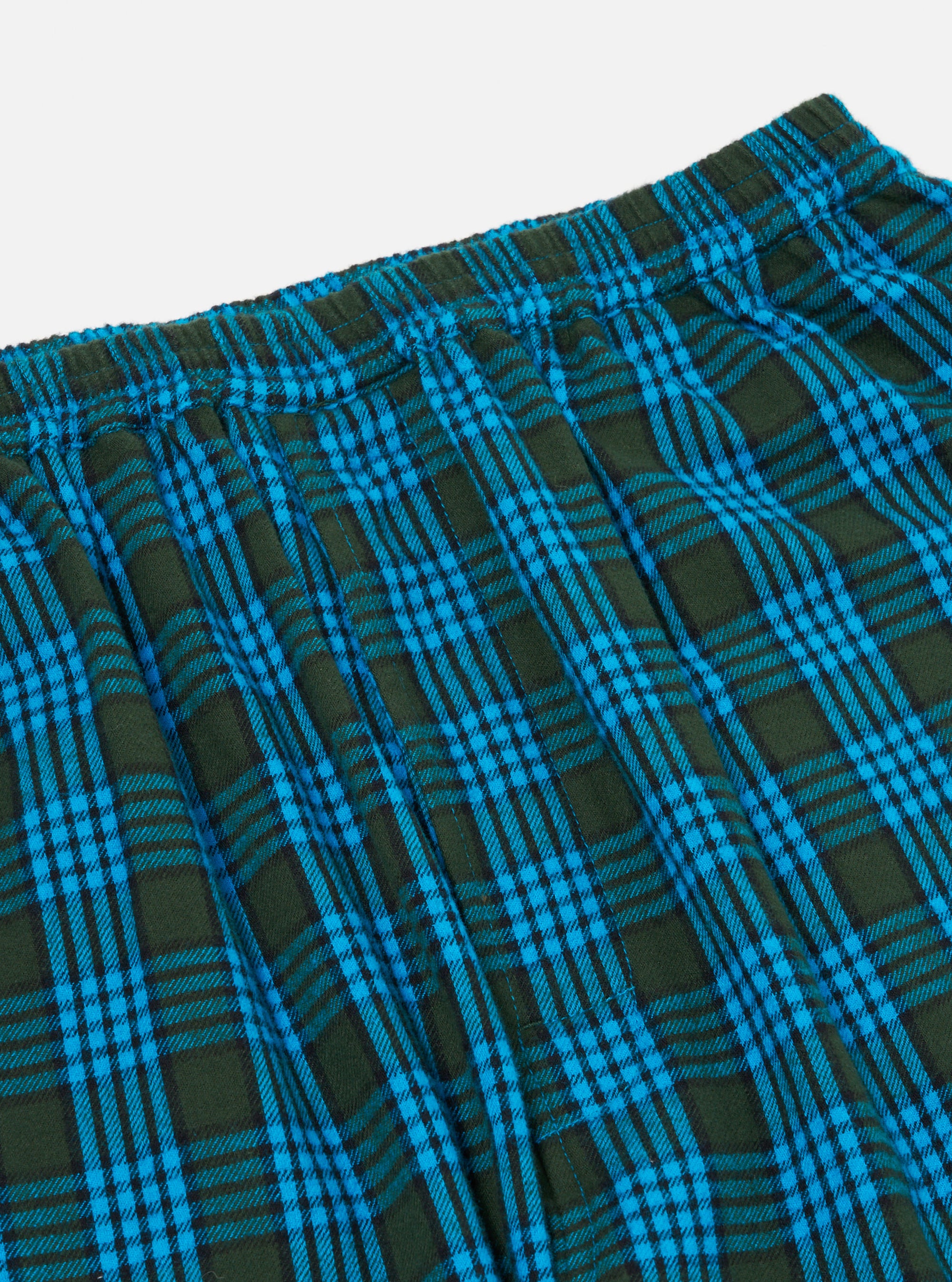 Close-up of the Blue Brushed Check Pyjama Pant. The brushed cotton fabric features a blue and dark green check pattern. Elasticated waistband. Shot on a white background.