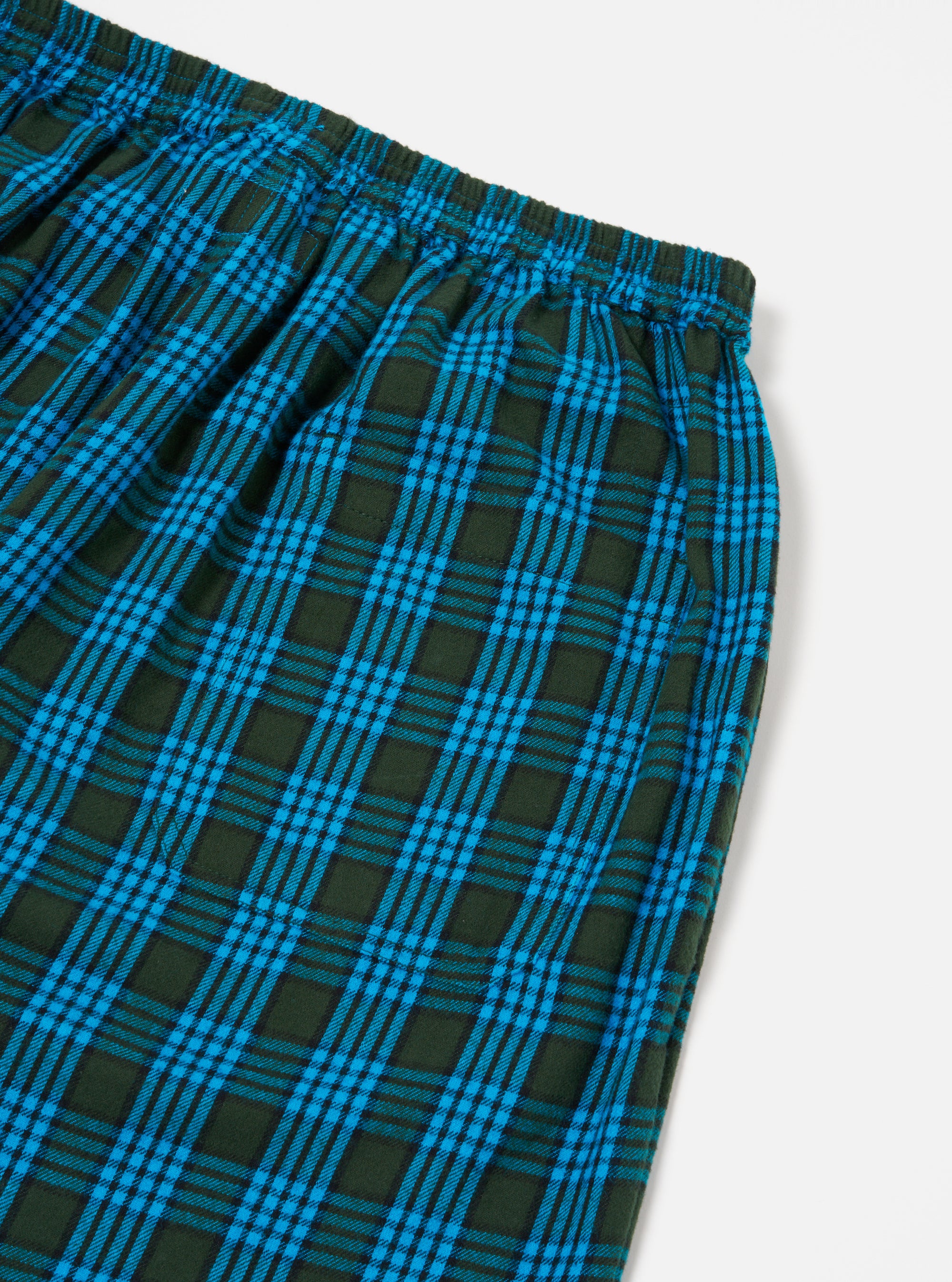 Close-up of the Blue Brushed Check Pyjama Pant on a white surface. The brushed cotton fabric features a blue and dark green check pattern. Elasticated waist detail visible.