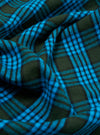 Close-up of the Blue Brushed Check Pyjama Pant fabric. The brushed texture features a blue and dark green check pattern. The fabric is draped to show its soft texture.