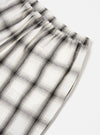 Close-up of the Ecru Shadow Check Pyjama Pant on a white surface. The relaxed fit pant features a shadow check pattern in ecru and grey tones, with an elastic waistband.
