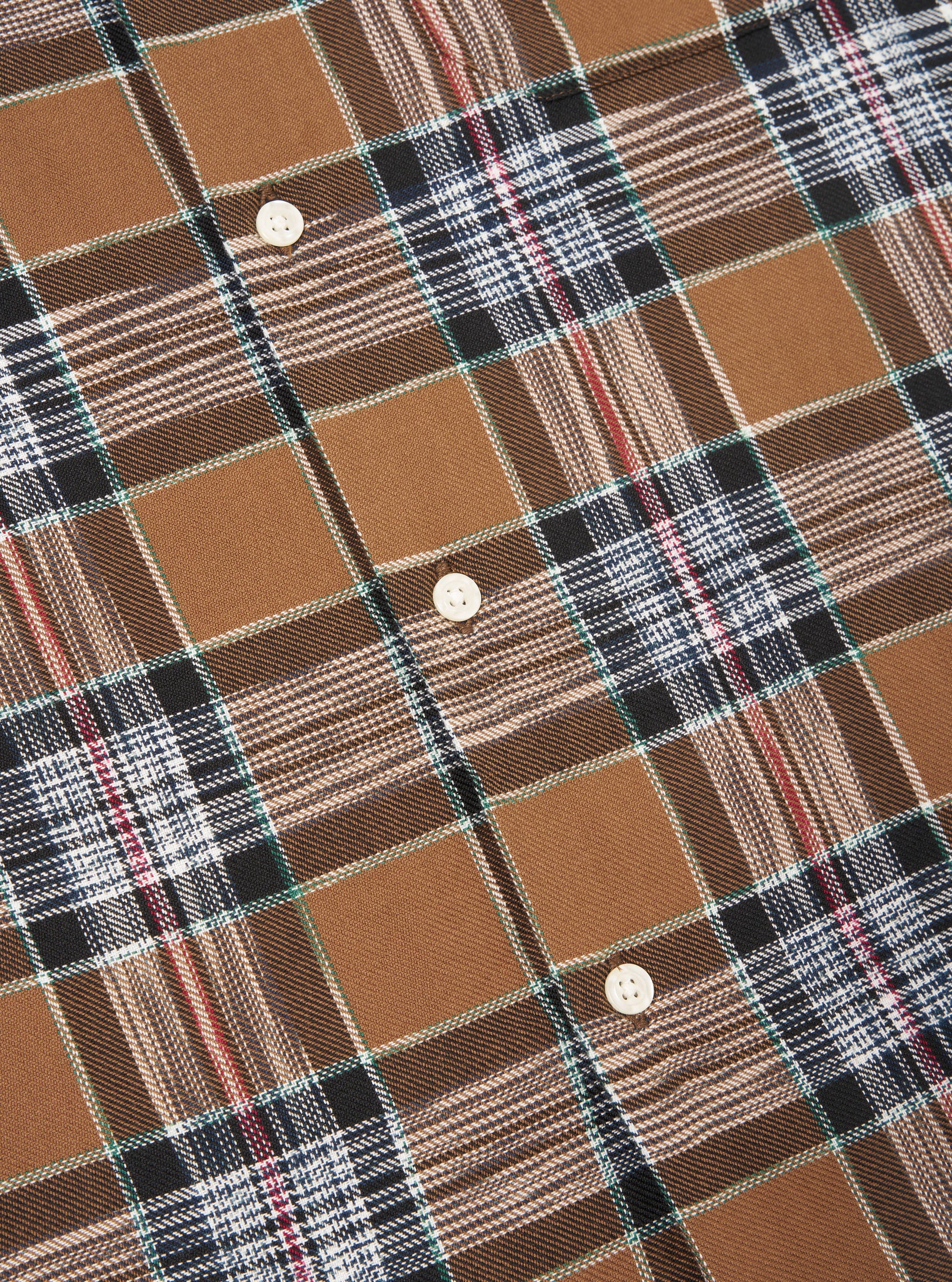 Close-up of the Brown Ikat Twill Check Long Pyjama Set. The fabric is a brown, white, black, and red plaid with white buttons.