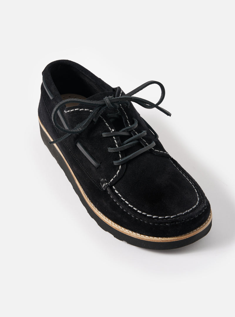 Studio shot of Zardus for Universal Works Black Suede Oliver shoe. The black suede lace-up shoe features contrast stitching and a light sole. Set against a white backdrop.