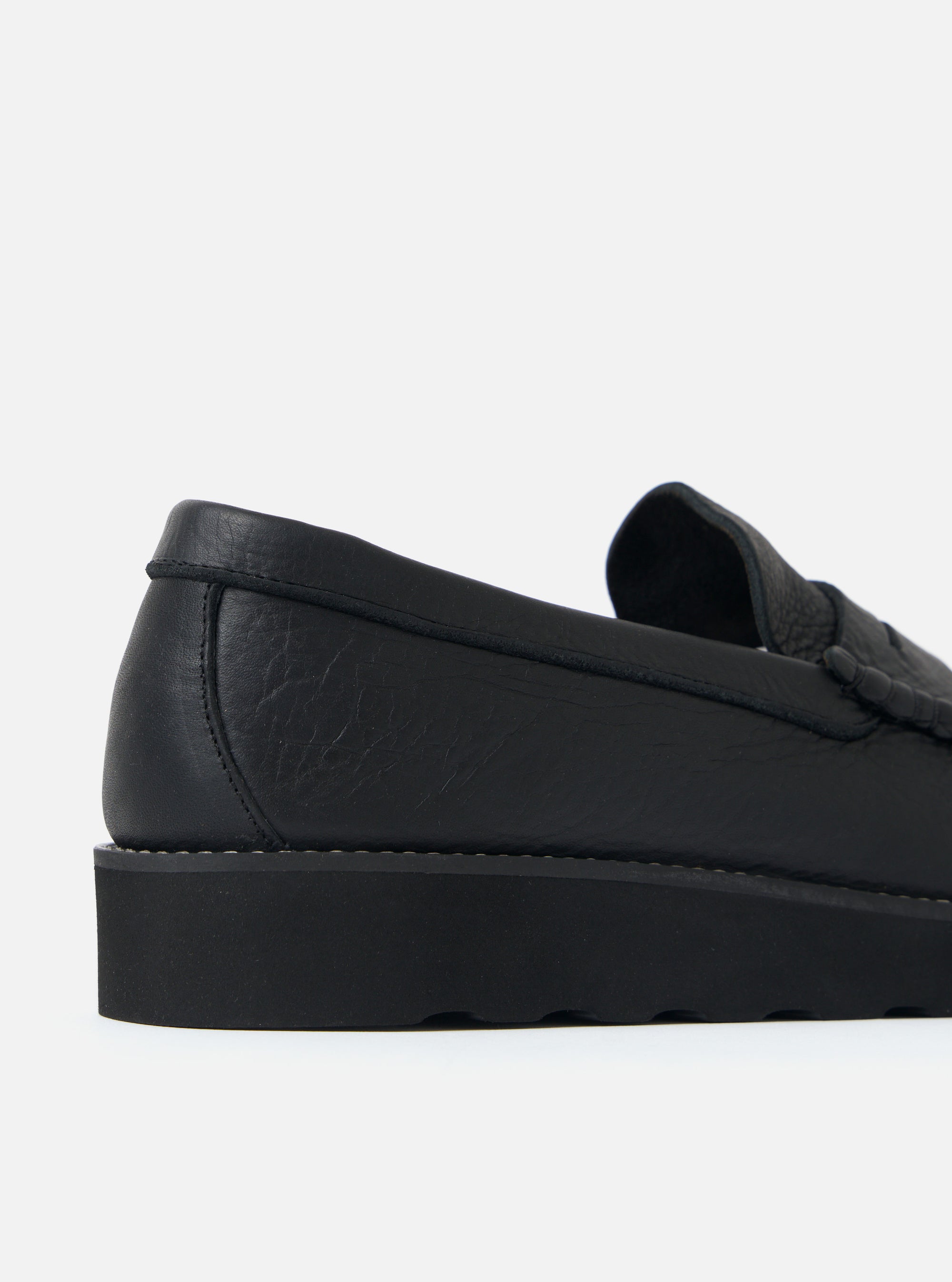 Close-up of a Zardus for Universal Works Black Leather Reggie Loafer on a white surface. The shoe features black leather and a chunky black sole.