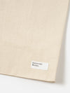 Close-up of an Ecru Canvas Market Tote on a white background. The canvas is a light beige color. A small white tag with "Universal Works." is sewn on.