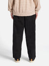 The Black Kelly Cotton Judo Pant is shown from a rear three-quarter angle as a flat lay against a plain white background. The image highlights the simple, wide-leg construction and the smooth texture of the black cotton fabric. The elasticated waistband and a rear patch pocket are visible.