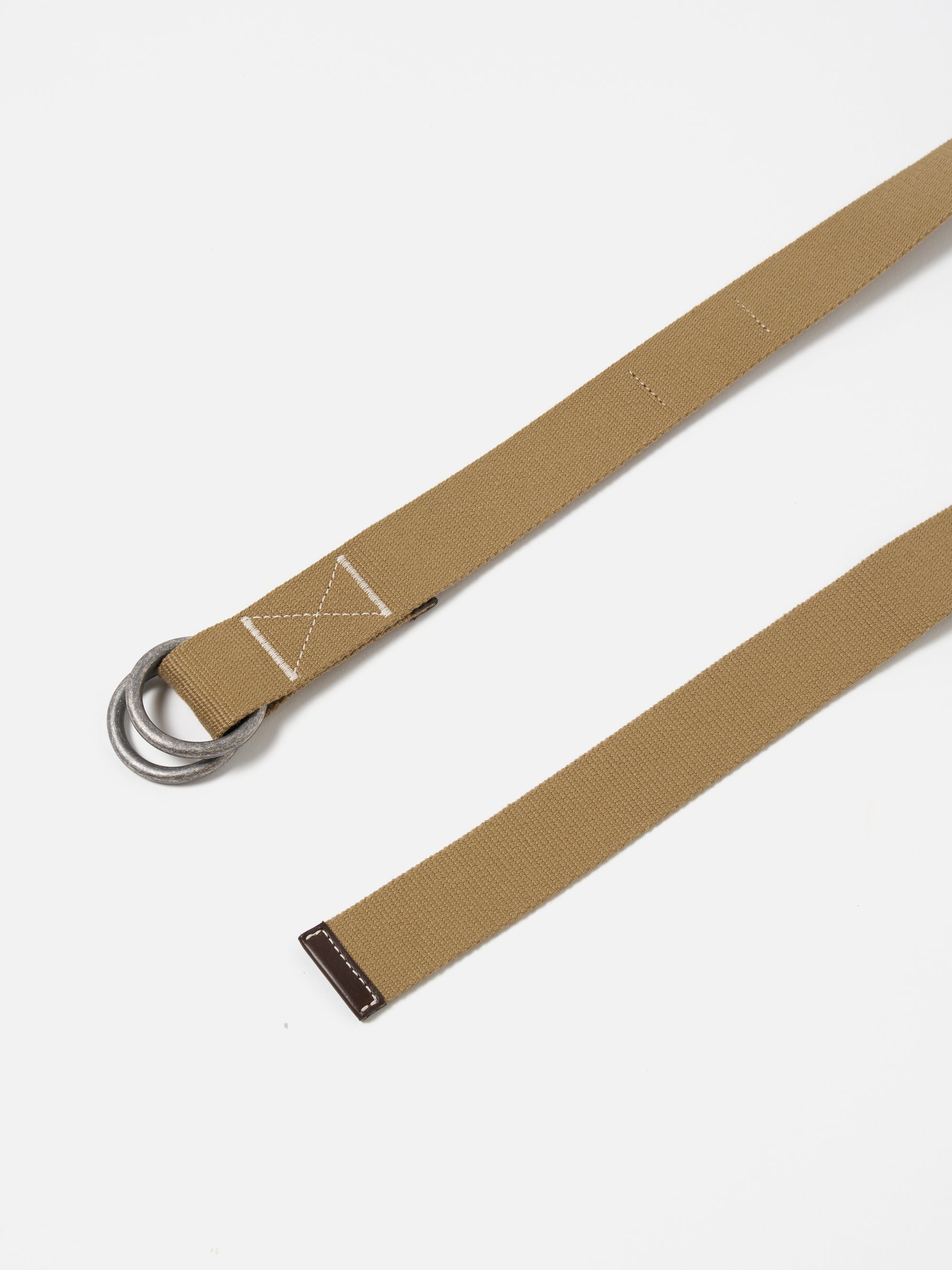 Close-up of a Dark Sand Canvas O Ring Belt on a white background. The canvas belt features a dark brown leather accent and silver-toned metal rings.